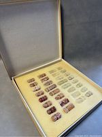 Complete set of 32 onyx stone chess pieces arranged in storage box with foam insert. Pieces are in two distinct stone colors, cream and reddish-brown, polished and carved.