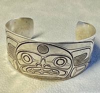 Angled view of silver cuff showing engraved raven face motif