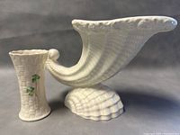 Side view of the Spode cornucopia planter beside the Belleek bud vase, showing the shape and design details.