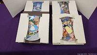 4 Disney collector plates in original cardboard boxes, showing partial artwork: Cinderella, Alice in Wonderland, Snow White, and Cinderella scenes.