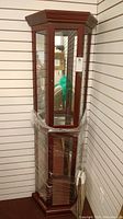 Full view of tall wooden display cabinet wrapped in protective plastic on bottom half.