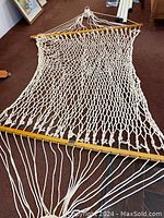 Full length view of white rope hammock with wooden spreader bars for support.