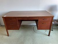 Front view of the vintage wooden desk showing six drawers and full top surface.