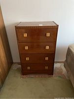 Front view of vintage 4-drawer wooden dresser with carved detailing and square wooden handles on drawers, showing wood finish and condition.