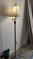 Full view of floor lamp showing tall metal and brass stem with large fabric shade.