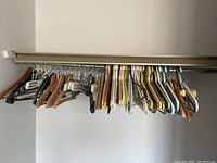 Photo showing a collection of wood and plastic hangers hung on a closet rod