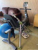 Photo showing Vision Fitness recumbent exercise bike, blue exercise ball, foot massager, ankle weights, and crutches around the bike.