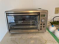 Front view of Black and Decker convection toaster oven showing glass door, control panel with dial and buttons, and digital screen.