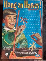 The colorful original game box showing a young boy playing Hang On Harvey! with bright yellow and red text, emphasizing vintage 1960s style.