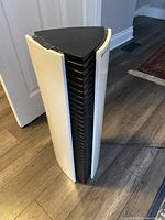 Front side view of Bionaire triangular air purifier showing white body with black vents and some wear on top corner.