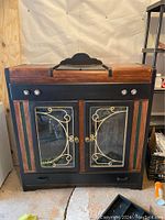 Front view of two-tone wood cabinet with glass doors and metal scrollwork
