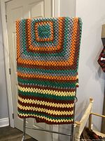 Crocheted afghan hanging over a chair, showing full pattern and colors