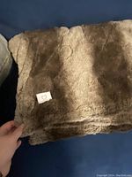 Brown faux fur electric blanket throw folded on blue couch, showing soft faux fur material and texture