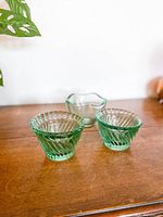 Front view of the three glass votive candle holders showing two green ribbed swirl holders and one clear scalloped holder.