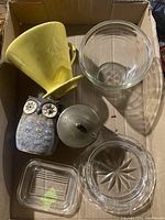 Box contents with yellow ceramic coffee dripper, clear glass bowl, owl figurine, metal lid, glass juicer, and rectangular glass dish