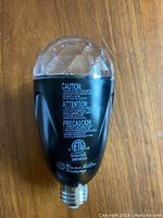 Close-up photo of the LED swirl light bulb showing the clear faceted dome and black base with caution text and certification labels