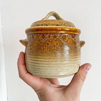 Front view of Mikasa ceramic sugar pot held in hand, showing gradient glaze from beige to brown and loop handle lid.