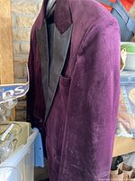 Purple men's velvet suit jacket hanging, showing the front, lapel, and pocket details.