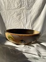Photo of round pottery dish showing front with glazed decorative design