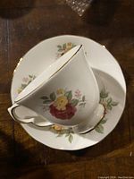 Top view of the teacup placed on the saucer showing the floral rose pattern and gold trim on both pieces