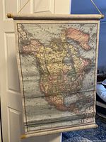 Fabric wall map hanging on a door, showing the continent of North America with visible country and state borders.