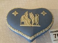 Top view of the blue heart-shaped Wedgwood trinket box with white classical relief figures and floral decorations on the lid.