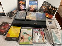 Samsung Blu-ray player with DVDs and exercise DVDs spread around it