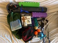 Complete set of fitness equipment laid out on white surface including resistance bands, rollers, massage balls, hand grip, jump rope, and accessories.