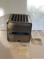 Front view of the Geizeer USB air conditioner device with freshener packet placed next to it, showing vented top and cubic shape.