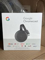 Front view of sealed Google Chromecast device in white retail packaging.