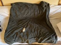 Twin size dark gray soft velvet-like weighted blanket laid out on bed.