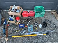Full view of all tools arranged on driveway including pickaxe, gas cans, tool case, saw, and other items
