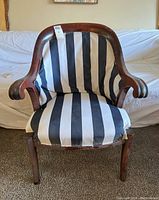 Front view of antique armchair showing striped upholstery and curved wooden arms