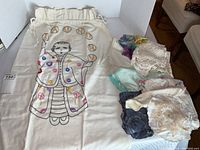 Full view of embroidered Chinese laundry drawstring bag next to a pile of various folded linens including lace and embroidery.