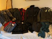 Various women's clothing items laid out on a bed including coats, jackets and tops in sizes small and medium.