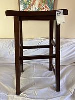 Side view of the dark brown wooden bar stool showing square legs and horizontal footrests