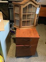 Wood wall display cabinet on top of laminate file cabinet, showing exterior condition and size.