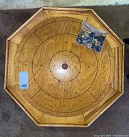 Top view of the Crokinole wooden game board with scoring rings and playing discs in a plastic bag on the board.