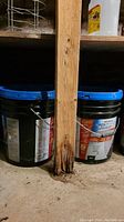 Two buckets visible behind wooden support post in basement.