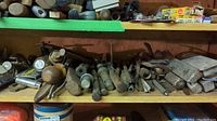 Shelf with various metal rods and bolts, some with wooden handles visible.