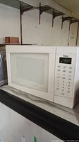 Side view of white Galaxy microwave showing digital control panel and numeric keypad.