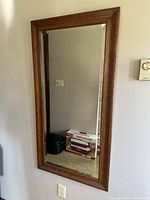 Front view of hanging rectangular wall mirror with wooden frame and beveled edges