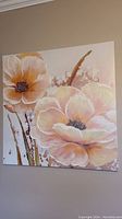 Front view of square canvas floral artwork featuring two large flowers in pastel peach and cream acrylic paint with beadwork centers.