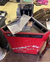 Front view of red metal sauna heater housing with Chromalox instruction sheet on top