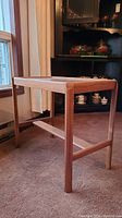 Side angle photo of wooden side table showing engraved legs and gloss finish