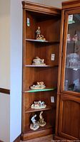 Full view of the Sklar Peppler five tier wood corner cabinet filled with several figurines on the shelves.