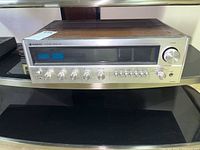 Sanyo stereo receiver DCX600K front view on a glass shelf showing multiple knobs, tuning dial, and display panel.