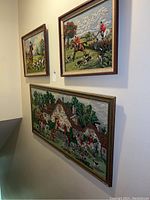 Three equestrian hunting needlepoint tapestries framed and hanging on a stairway wall, showing overall set and detail of size and framing.