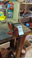 View of red Woden table vice mounted on wooden workbench with user tag attached.