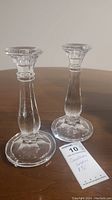 Two clear glass candle holders are shown standing upright on a wooden surface with a tag showing 'candle holders 8'''.